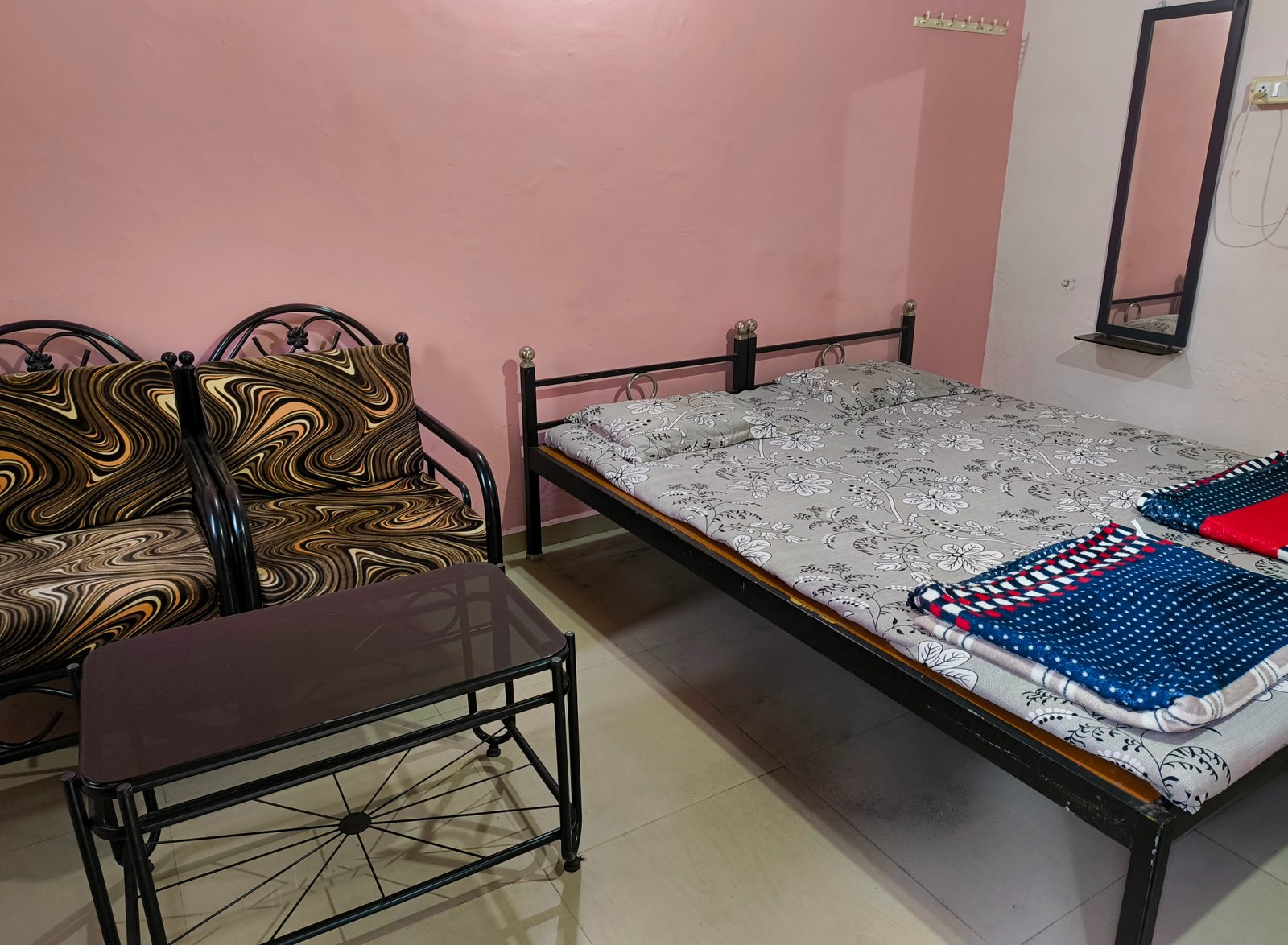 A clean homestay room with a double bed and a small seating area